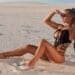 Sexy woman in swimsuit enjoying summer sun and tanning on the beach